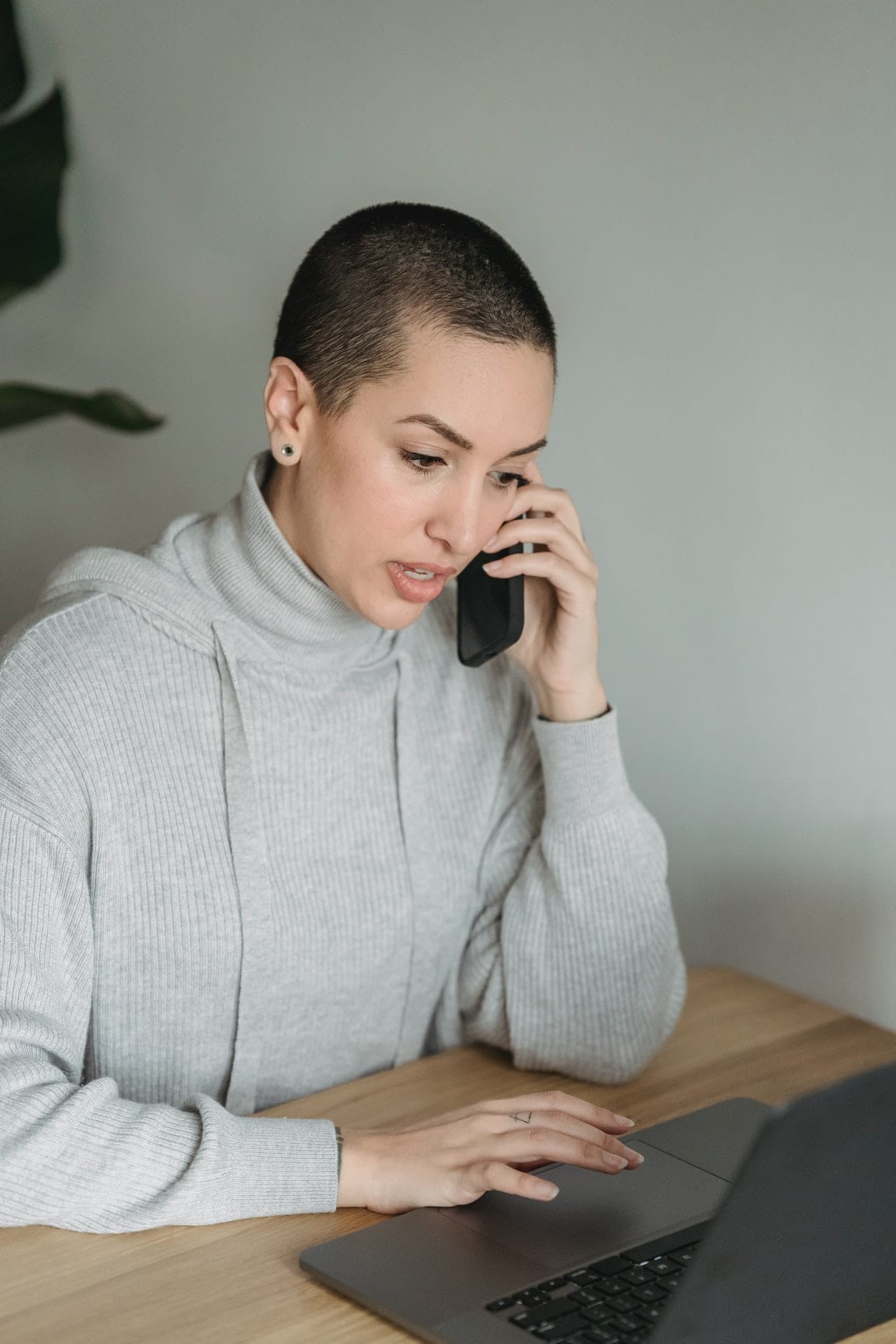 Androgynous person with dark hair and buzz cut talking on their cell phone.