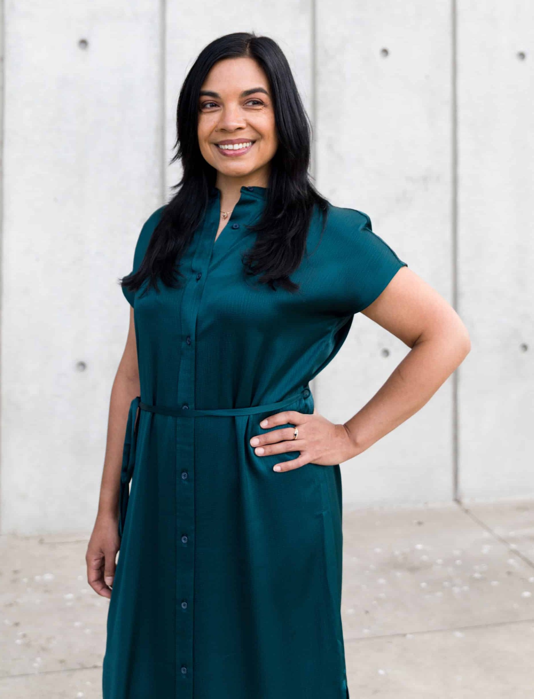 Headshot of Maya Borgueta, San Francisco Psychologist, standing on the street in downtown San Francisco. She is a Millennial Filipinx woman with long hair and is wearing a green goat and striped shirt. 